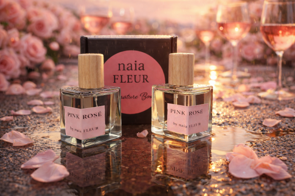 PINK TRIO BOTTLES Naia FLEUR Pink Collection perfume bottles with wood caps on warm glowing background.